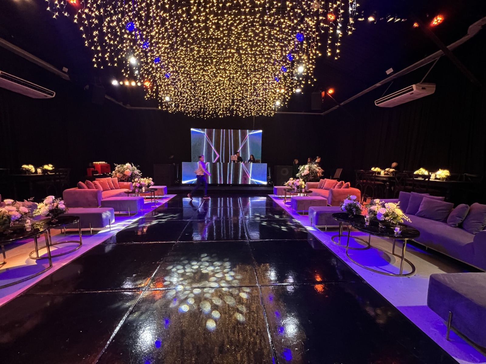Pista de baile con cielo de luces doradas y sillones violetas